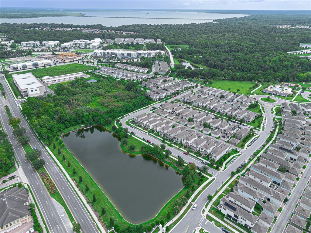 An aerial view shows a residential neighborhood with a large pond and nearby commercial buildings — 225 GENTLE BREEZE LANE, WINTER SPRINGS, FL