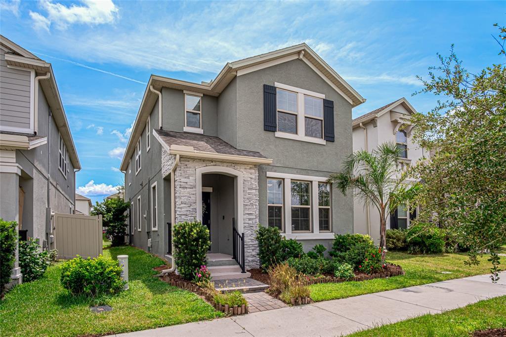 A two-story house with gray stucco siding, stone accents, and a front walkway — 225 GENTLE BREEZE LANE, WINTER SPRINGS, FL