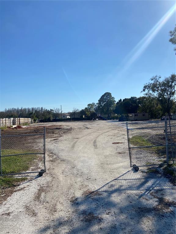 A fenced, unpaved lot features tire tracks leading toward trees and a small structure — 14024 STATE ROAD 54, ODESSA, FL