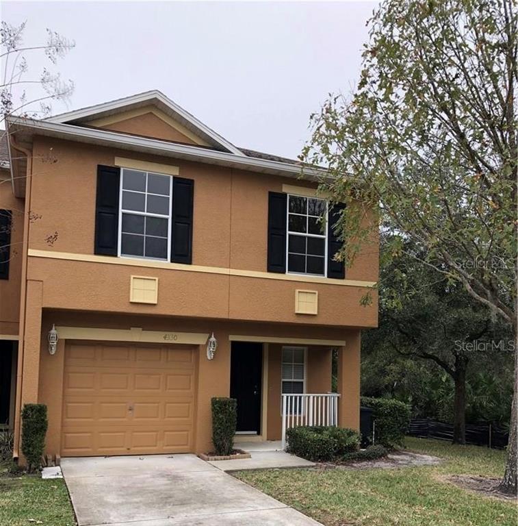 A two-story tan townhouse with a single-car garage and black shutters on the upper windows — 4330 ARISTOCRAT POINT, OVIEDO, FL