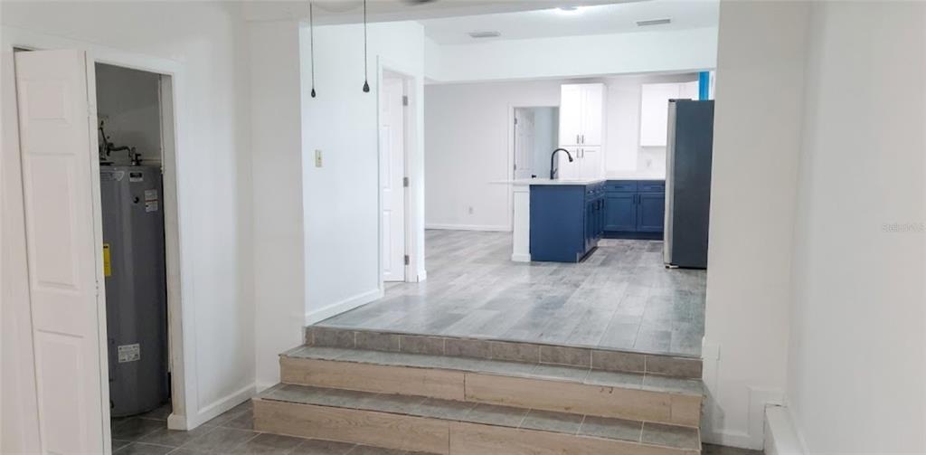 A view from a tiled lower level up two steps into a kitchen with blue cabinetry — 210 S 15TH STREET, PALATKA, FL