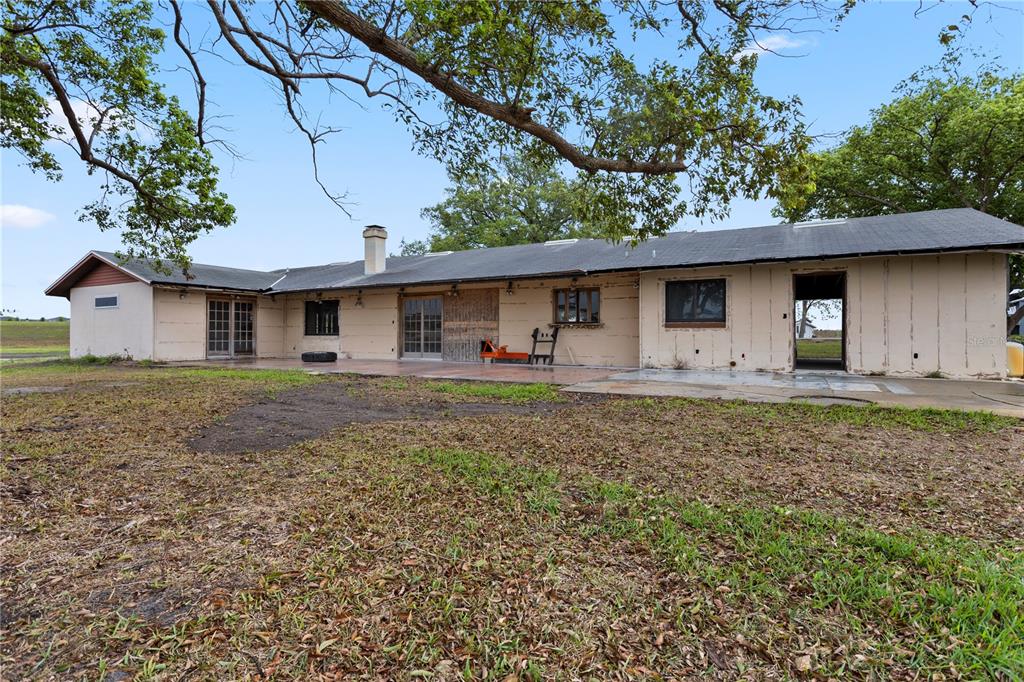 The exterior of a single-story house with unfinished siding and a large backyard — 17425 LAKE INGRAM ROAD, WINTER GARDEN, FL