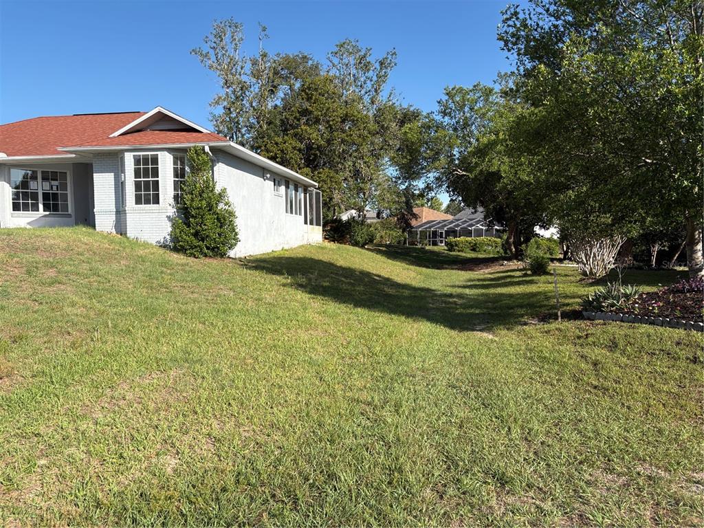 A side view of a house with a red roof and a grassy yard — 4422 N RATH RUE POINT, BEVERLY HILLS, FL