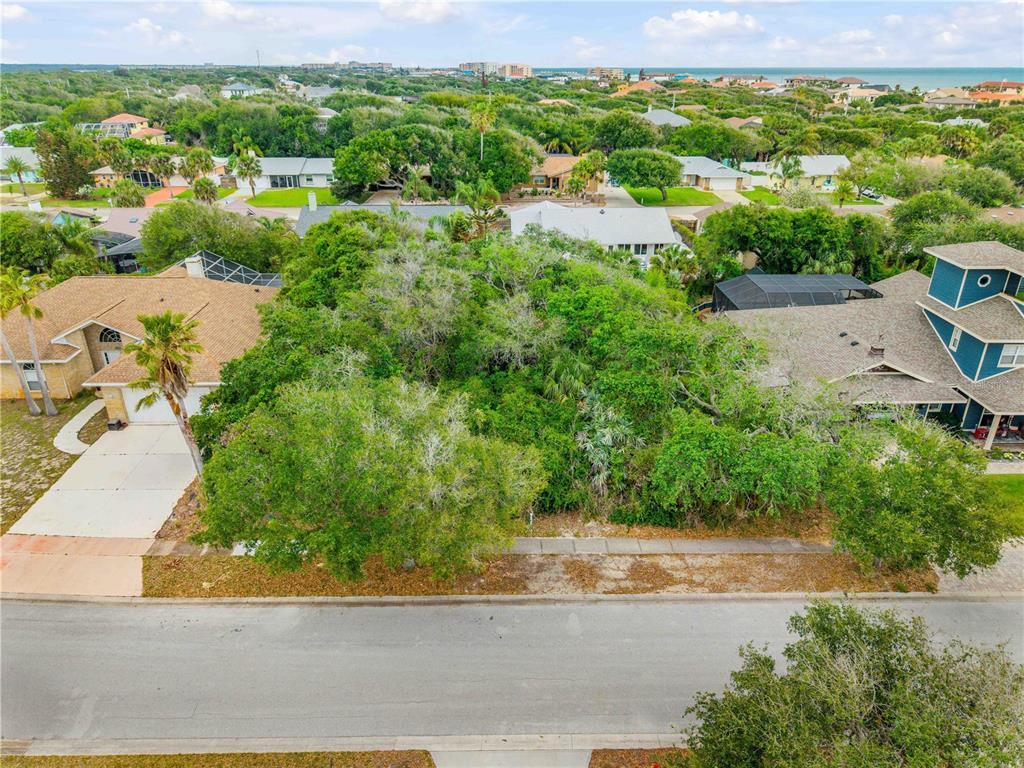 An aerial view shows a vacant, tree-covered lot situated between two residential houses — 70 OCEAN WAY DRIVE, PONCE INLET, FL