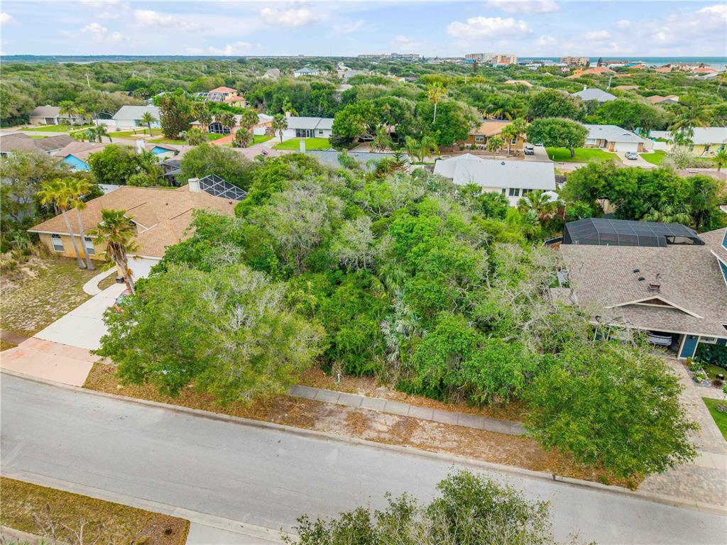 An aerial view shows a vacant, tree-covered residential lot situated between two houses — 70 OCEAN WAY DRIVE, PONCE INLET, FL
