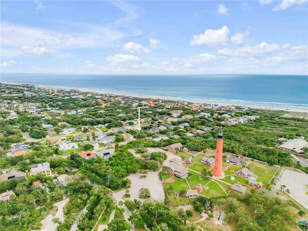 An aerial view shows a lighthouse near a coastal neighborhood and the ocean — 70 OCEAN WAY DRIVE, PONCE INLET, FL