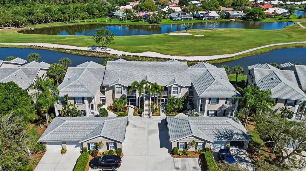 An aerial view of a multi-unit residential building with a golf course and pond nearby — 115 WOODBRIDGE DRIVE UNIT 201, VENICE, FL