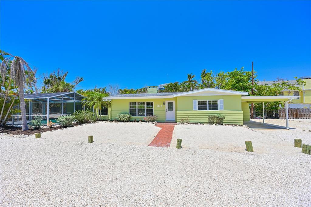 A light green single-story house features a gravel front yard and a covered carport — 5924 GULF OF MEXICO DRIVE, LONGBOAT KEY, FL