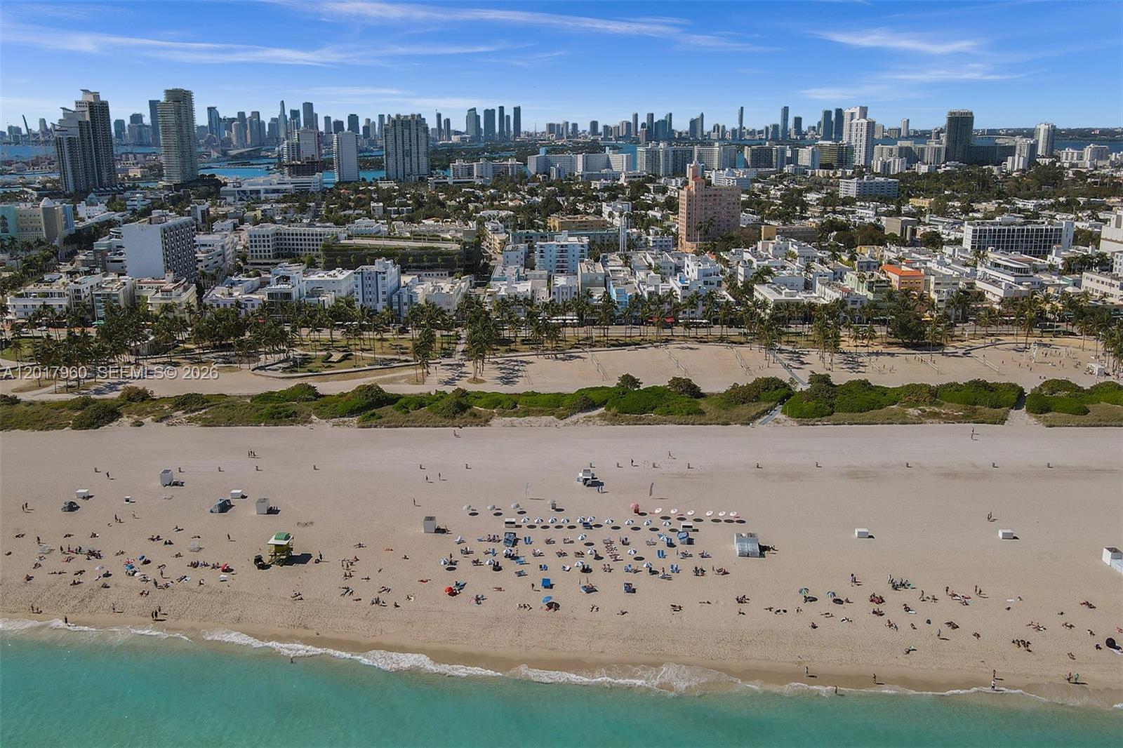 An aerial view of a sandy beach with umbrellas and the Miami skyline in the background — 713 Collins Ave # 42, Miami Beach FL 33139, MIAMI BEACH, FL