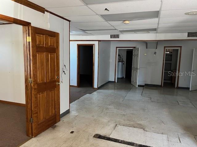 An interior view of a commercial space with a wooden door, drop ceiling, and tile flooring — 10802 MAIN STREET UNIT A, THONOTOSASSA, FL