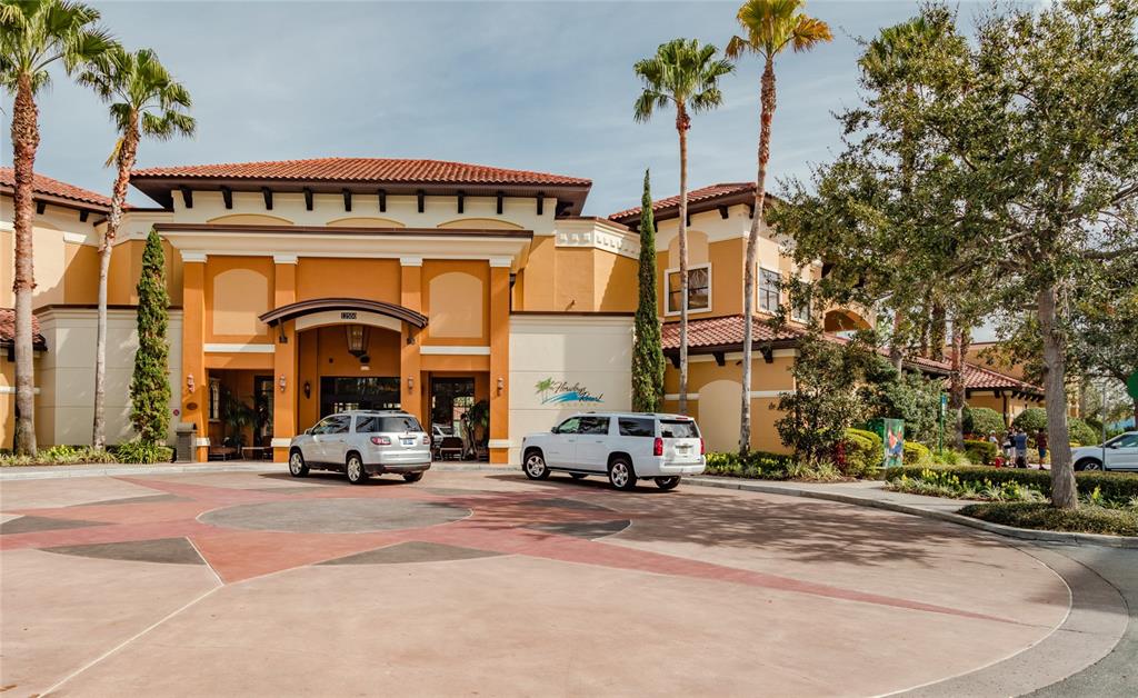 The exterior of a multi-story resort building features a circular driveway and palm trees — 12539 FLORIDAYS RESORT DRIVE UNIT 211D, ORLANDO, FL