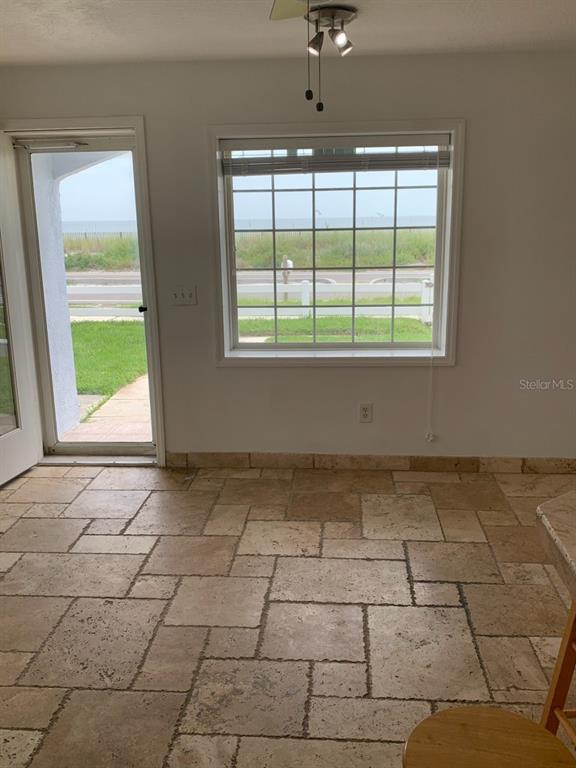 A room with stone tile flooring, a glass door, and a window overlooking the beach — 1908 S OCEAN SHORE BOULEVARD UNIT B, FLAGLER BEACH, FL