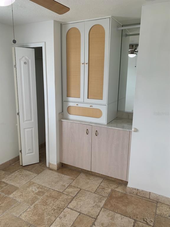 A vanity area features a white cabinet with rattan accents, a stone countertop, and tiled flooring — 1908 S OCEAN SHORE BOULEVARD UNIT B, FLAGLER BEACH, FL