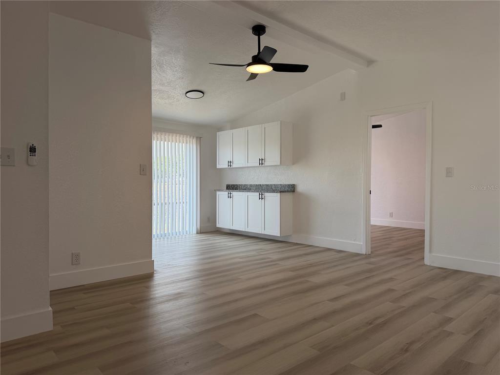 A room with light wood-look flooring, white cabinets, a ceiling fan, and a sliding glass door — 514 GREENBROUGH DRIVE, LAKE WALES, FL