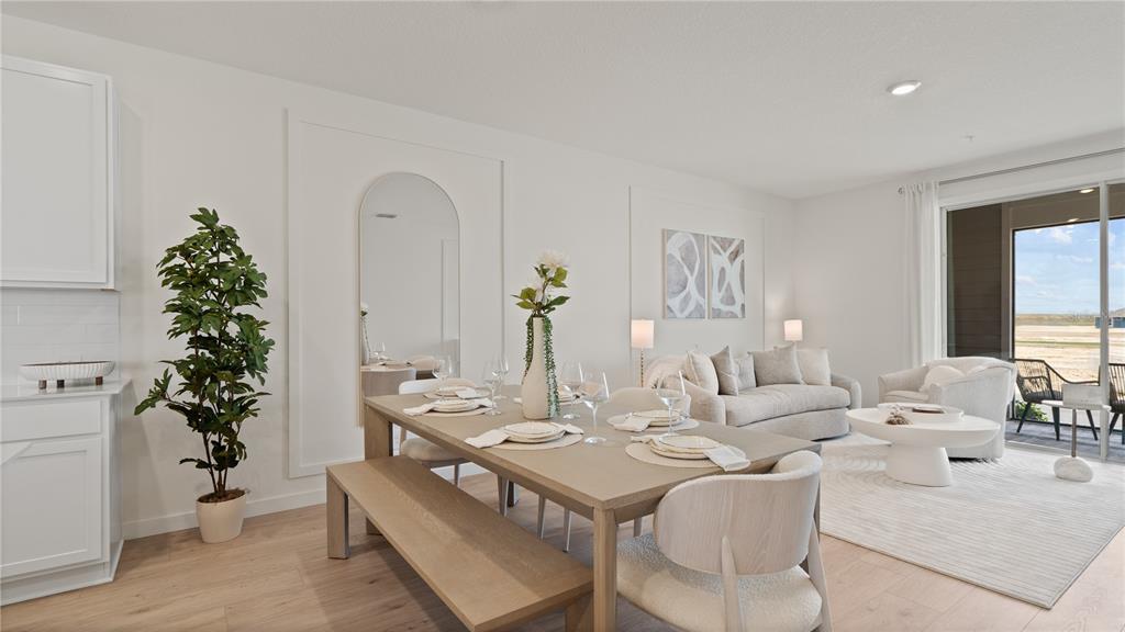A dining area with a wooden table and bench sits beside a living room — 5379 WHISPERING GARDEN WAY, CLERMONT, FL