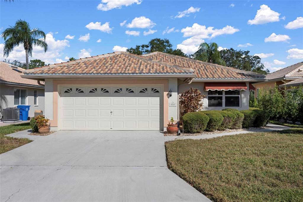 A single-story house with a beige stucco exterior, a tile roof, and a two-car garage — 4310 TURNBERRY COURT, BRADENTON, FL