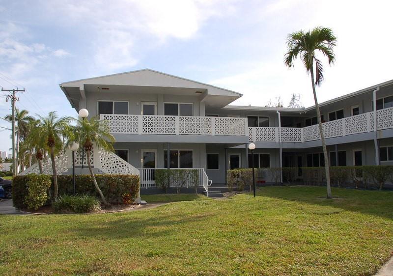 A two-story apartment building with a white lattice balcony and palm trees on the lawn — 600 Layne Boulevard # 201, Hallandale Beach FL 33009, HALLANDALE BEACH, FL