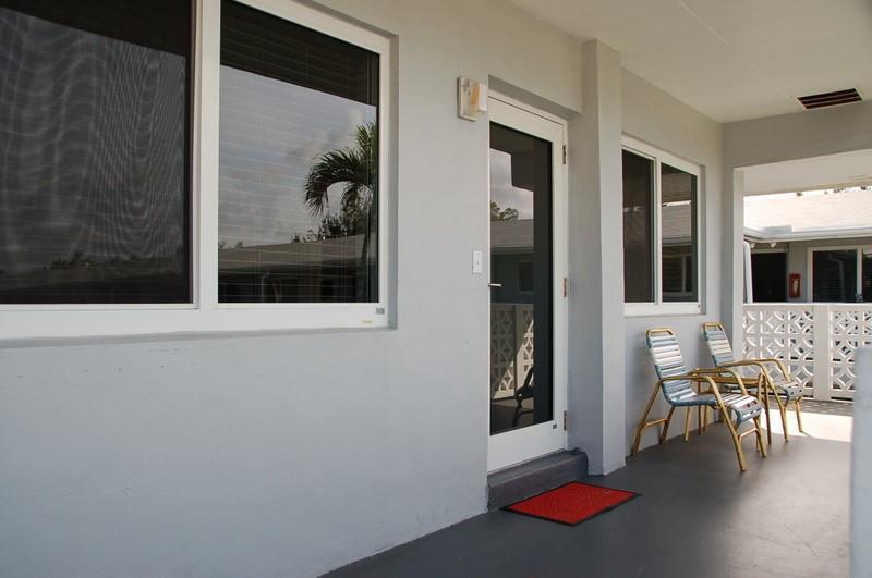 A gray exterior patio features a glass door, two windows, and two metal lawn chairs — 600 Layne Boulevard # 201, Hallandale Beach FL 33009, HALLANDALE BEACH, FL