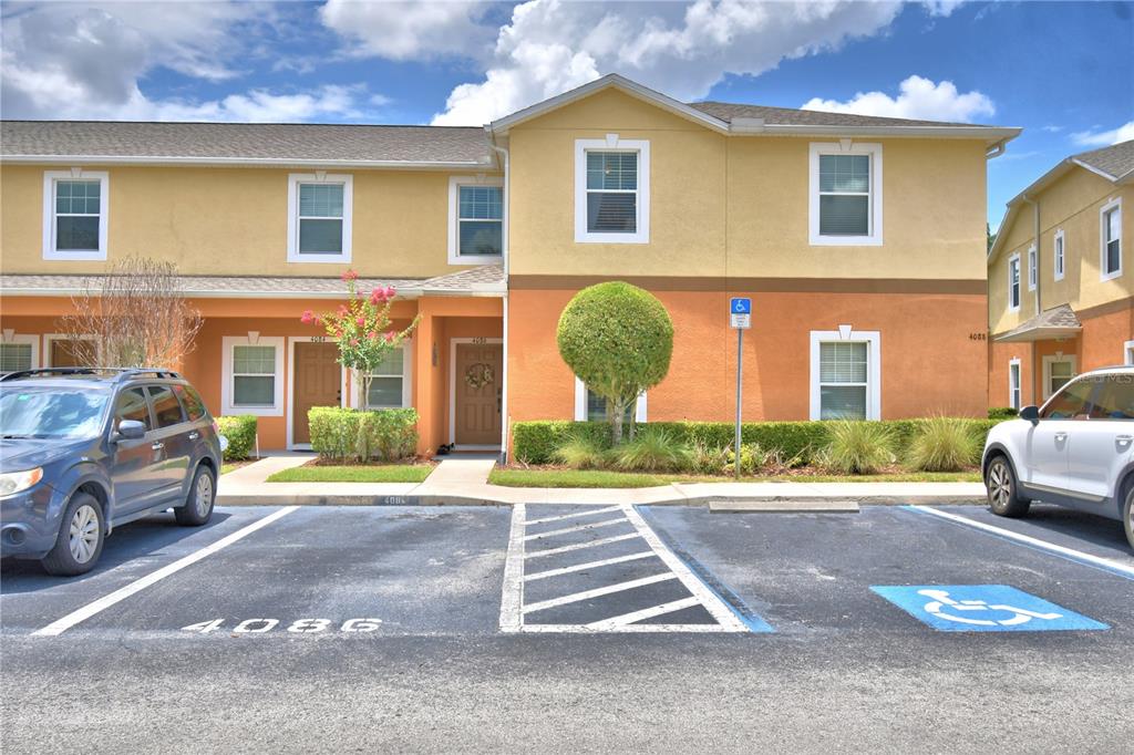 A two-story townhouse exterior features tan and orange stucco walls with a parking lot — 4086 WINDING VINE, LAKELAND, FL