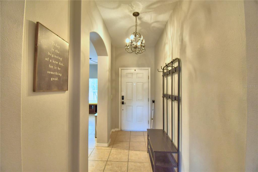 A tiled entryway features a coat rack, a wall sign, and a chandelier — 4086 WINDING VINE, LAKELAND, FL