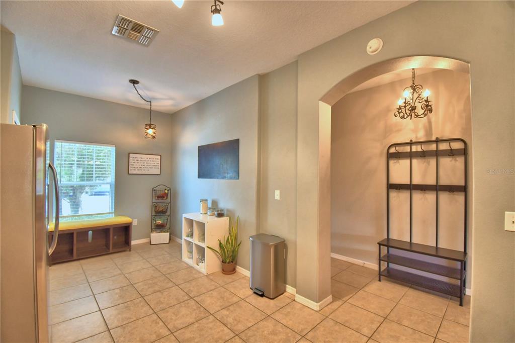 A tiled kitchen area features a window bench, a metal coat rack, and arched entryways — 4086 WINDING VINE, LAKELAND, FL