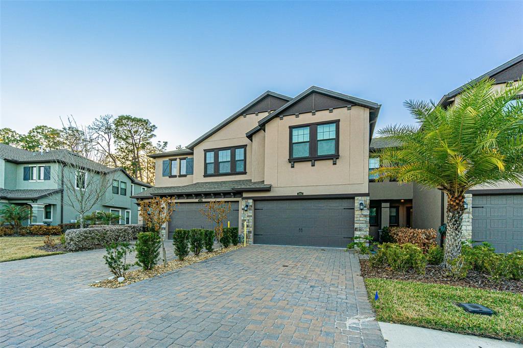 A two-story house with a beige stucco exterior, stone accents, and a paved driveway — 5062 SAN MARTINO DRIVE, WESLEY CHAPEL, FL