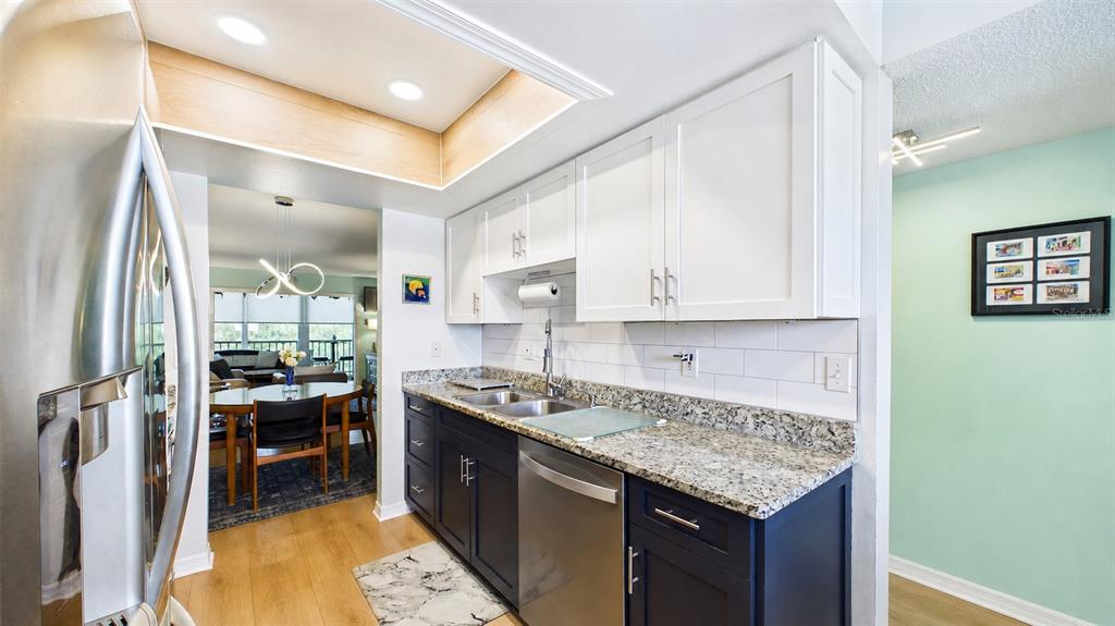 A kitchen features white upper cabinets, dark lower cabinets, granite countertops, and stainless steel appliances — 5775 PARK STREET N UNIT 410, ST PETERSBURG, FL