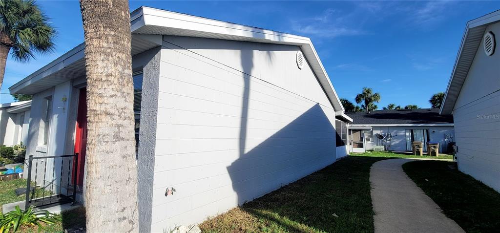 A side view of a light-colored concrete block house with a palm tree in front — 13 LAKE VILLA WAY, KISSIMMEE, FL