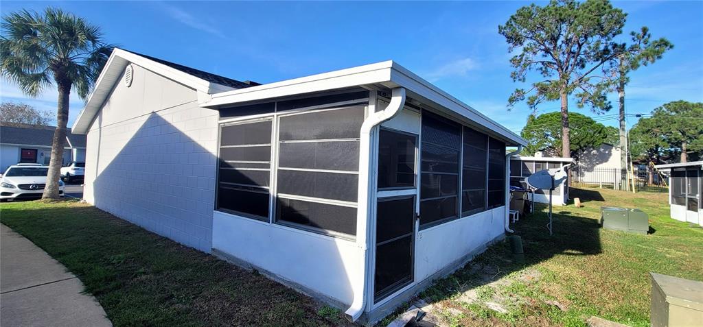 The exterior of a white concrete block house features a screened-in porch and a palm tree — 13 LAKE VILLA WAY, KISSIMMEE, FL