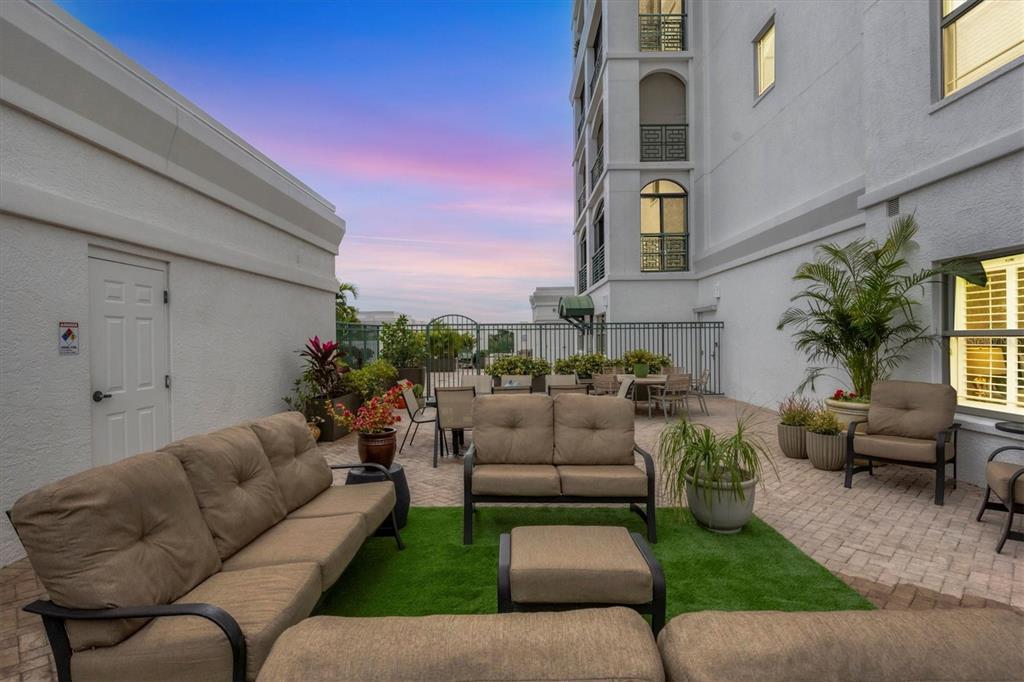 An outdoor patio area features patio furniture, artificial turf, and a view of a building — 505 S ORANGE AVENUE UNIT 301, SARASOTA, FL