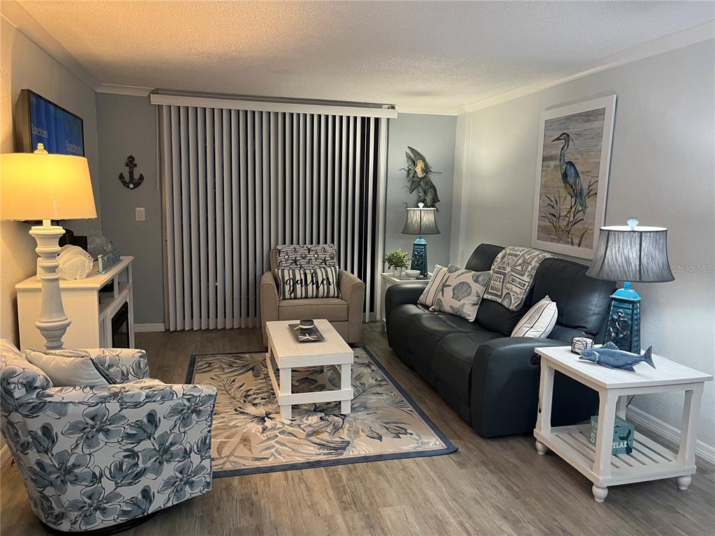 A coastal-themed living room features a dark sofa, patterned armchairs, and a white coffee table — 2727 N ATLANTIC AVENUE UNIT 414, DAYTONA BEACH, FL