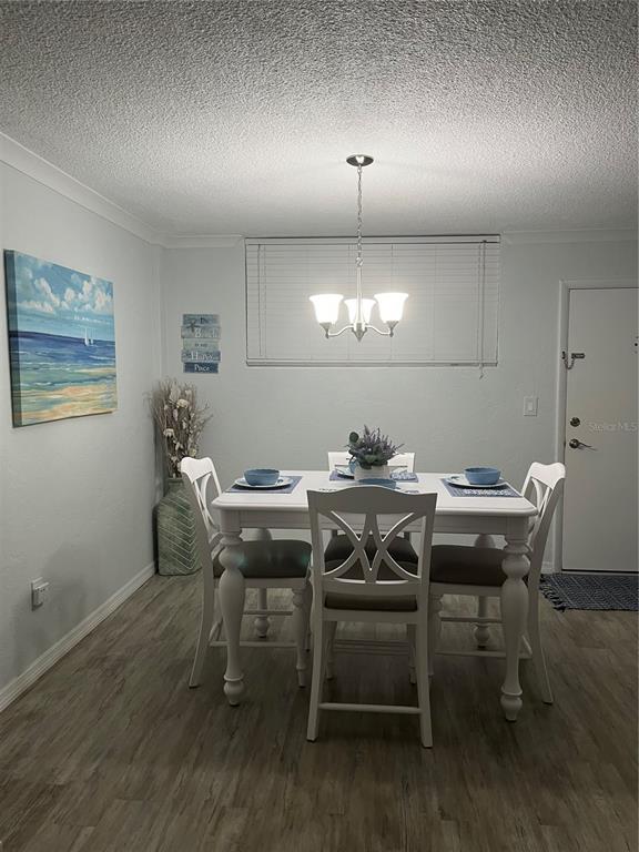 A dining room with a white table, four chairs, a chandelier, and wood-look flooring — 2727 N ATLANTIC AVENUE UNIT 414, DAYTONA BEACH, FL