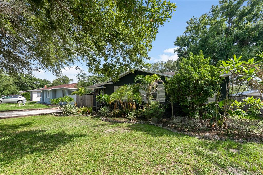 A dark-painted single-story house with a front yard, landscaping, and mature trees — 1010 W BERRY AVENUE, TAMPA, FL