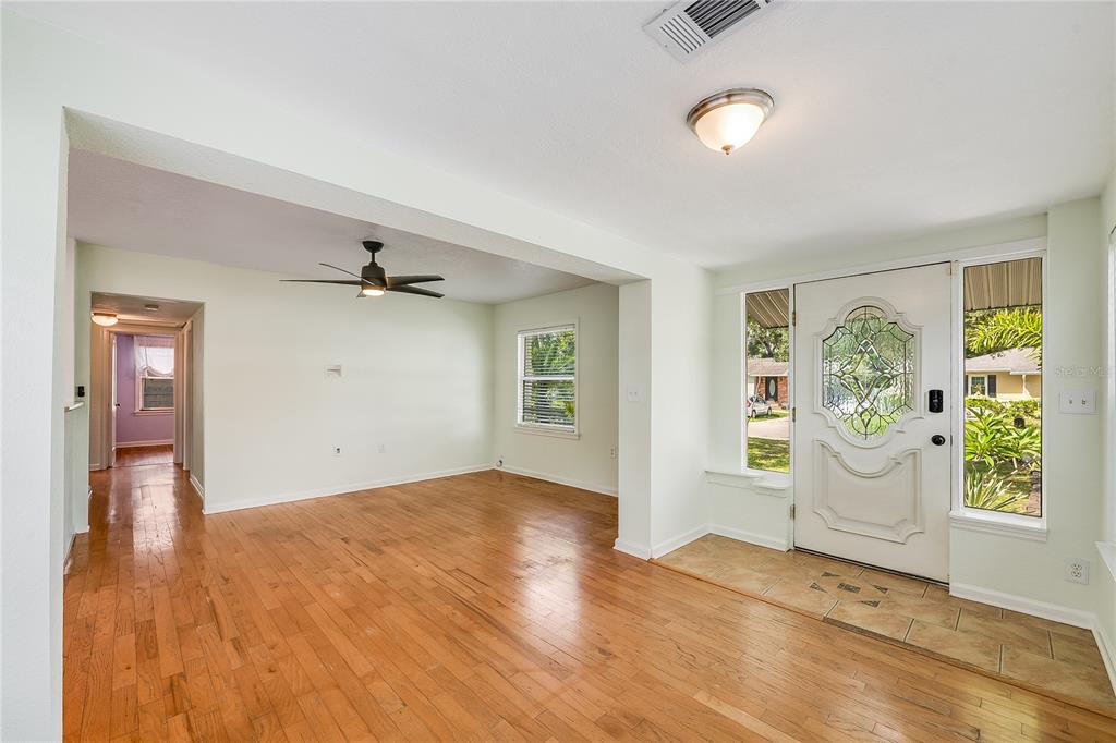 A living room with hardwood floors, a ceiling fan, and a front door with glass — 1010 W BERRY AVENUE, TAMPA, FL