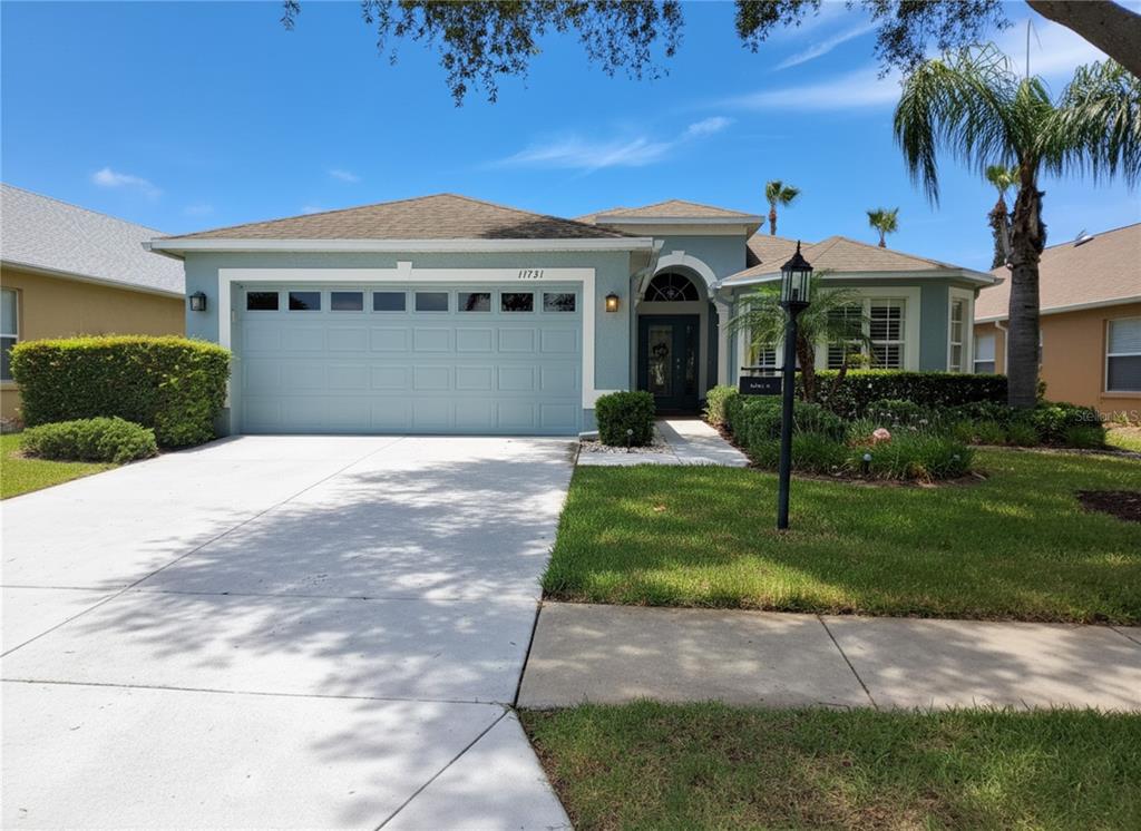 A single-story house with a light blue exterior, a two-car garage, and a landscaped yard — 11731 HERITAGE POINT DRIVE, HUDSON, FL