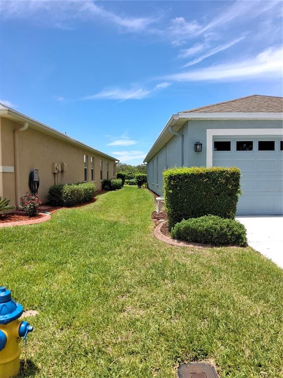 A grassy yard sits between two suburban houses under a bright blue sky — 11731 HERITAGE POINT DRIVE, HUDSON, FL