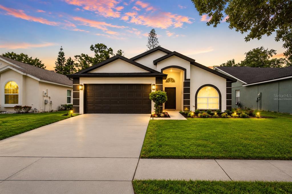 A single-story house with a two-car garage, white stucco walls, and a dark shingled roof — 6808 YARDLEY OAKS COURT, TAMPA, FL