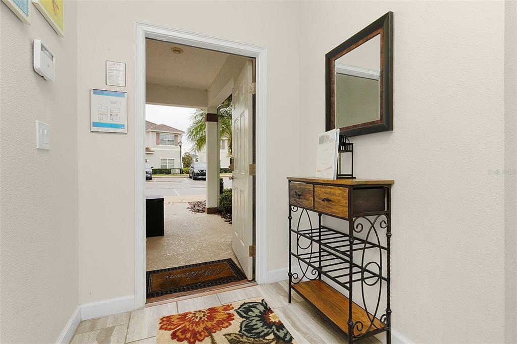 An entryway features a tiled floor, a console table with a mirror, and an open door — 3148 PEQUOD PLACE, KISSIMMEE, FL