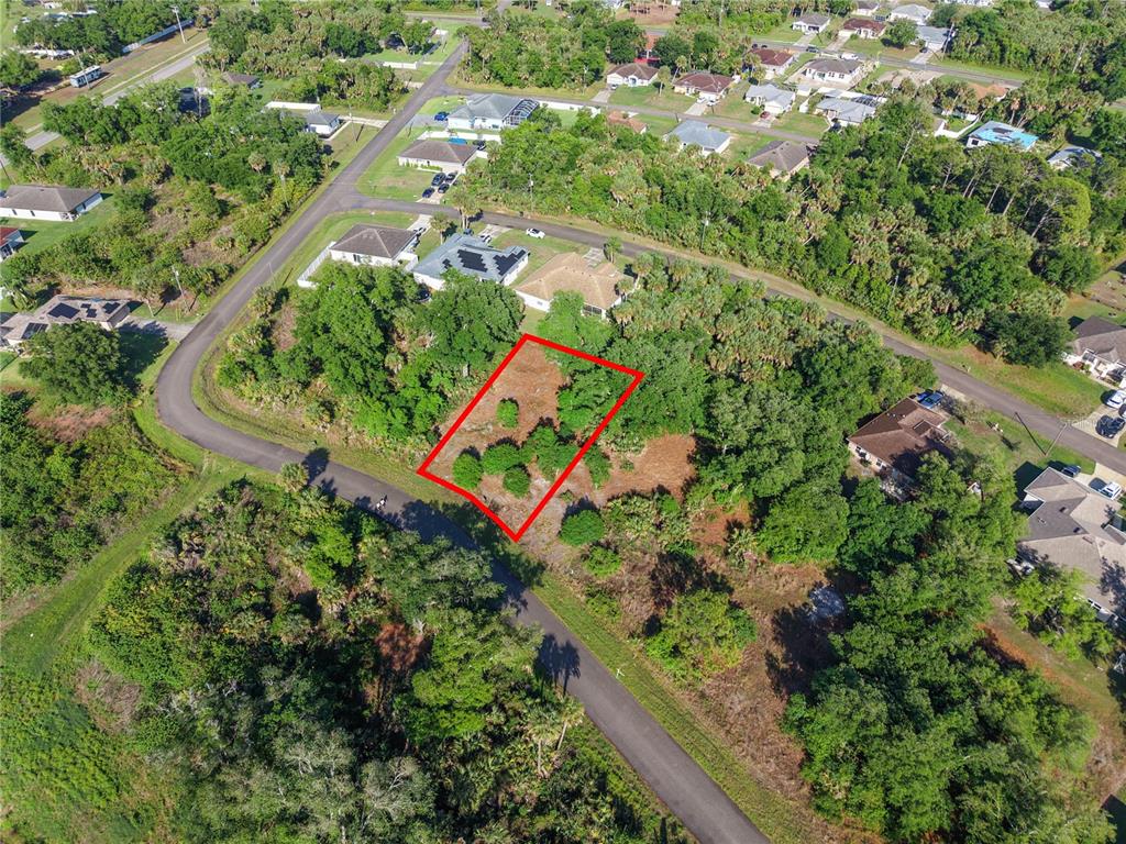 An aerial view shows a vacant, wooded residential lot outlined in red between paved roads — GOSHEN ROAD, NORTH PORT, FL