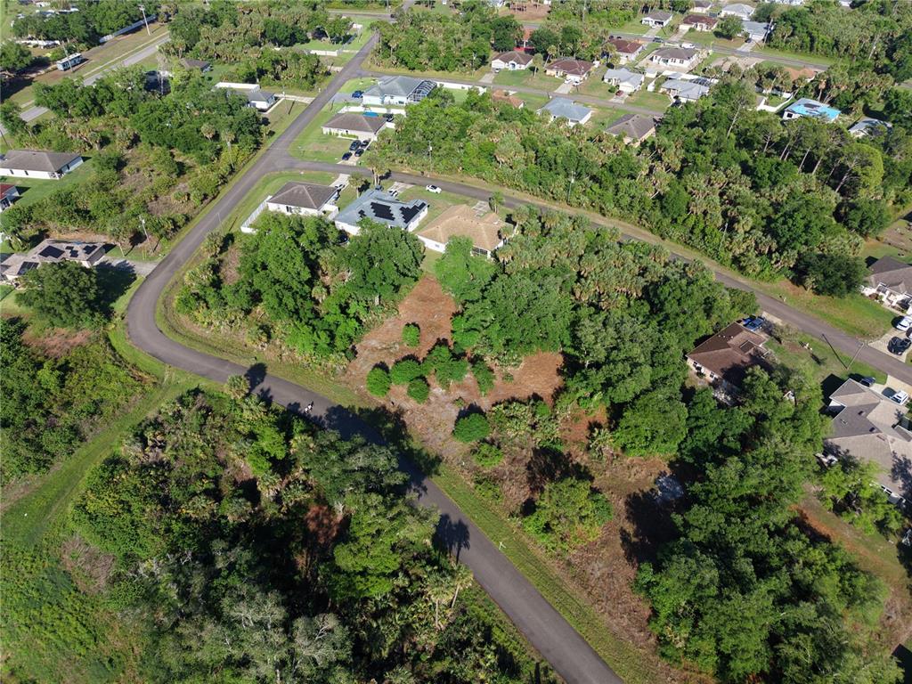 An aerial view shows a vacant, wooded residential lot surrounded by houses and paved streets — GOSHEN ROAD, NORTH PORT, FL
