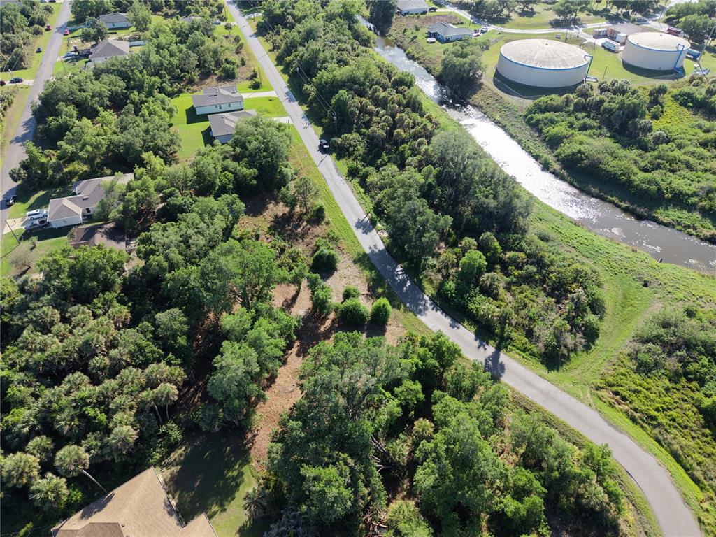 An aerial view shows a road running between a wooded residential area and a canal — GOSHEN ROAD, NORTH PORT, FL