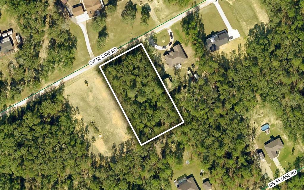 This aerial view shows a rectangular, wooded vacant lot outlined in white along a road — 12440 SW 52ND LANE ROAD, OCALA, FL
