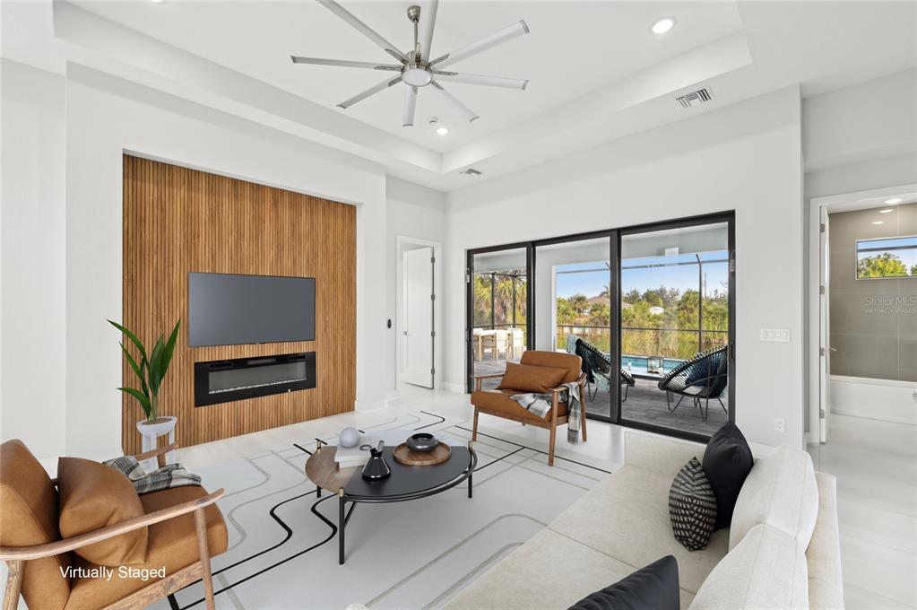 A living room features a wood-slat accent wall with a fireplace, television, and sliding glass doors — 9516 PRESIDENT CIRCLE, PORT CHARLOTTE, FL