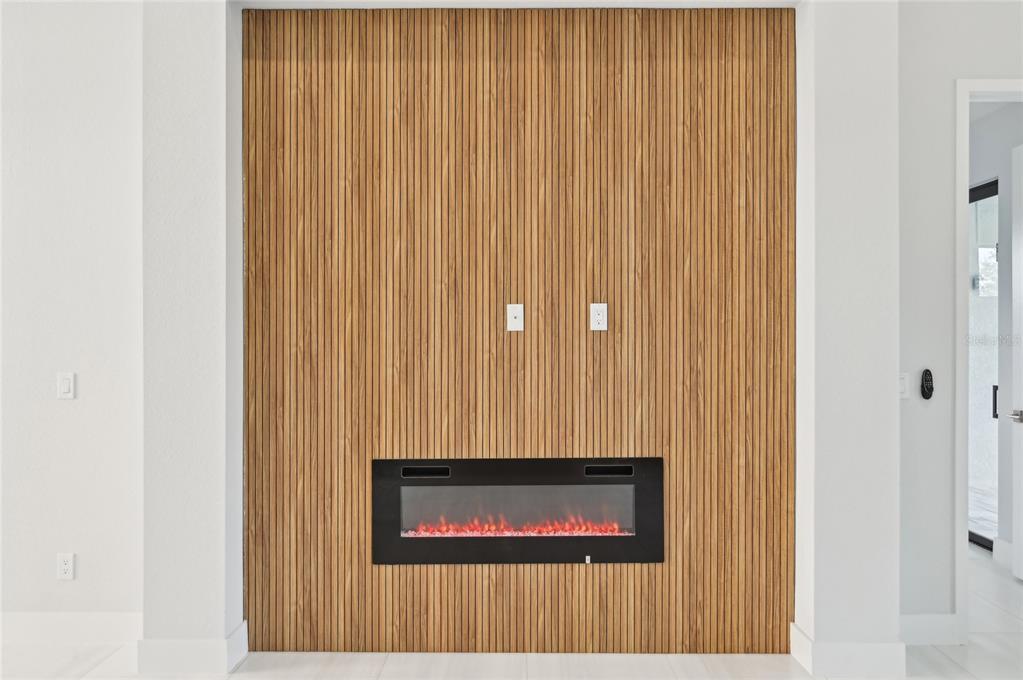 A wall with vertical wood slats features a built-in electric fireplace and wall-mounted power outlets — 9516 PRESIDENT CIRCLE, PORT CHARLOTTE, FL