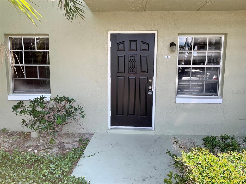 A black front door is centered between two windows on a light green exterior wall — 525 CONWAY ROAD UNIT 9, ORLANDO, FL