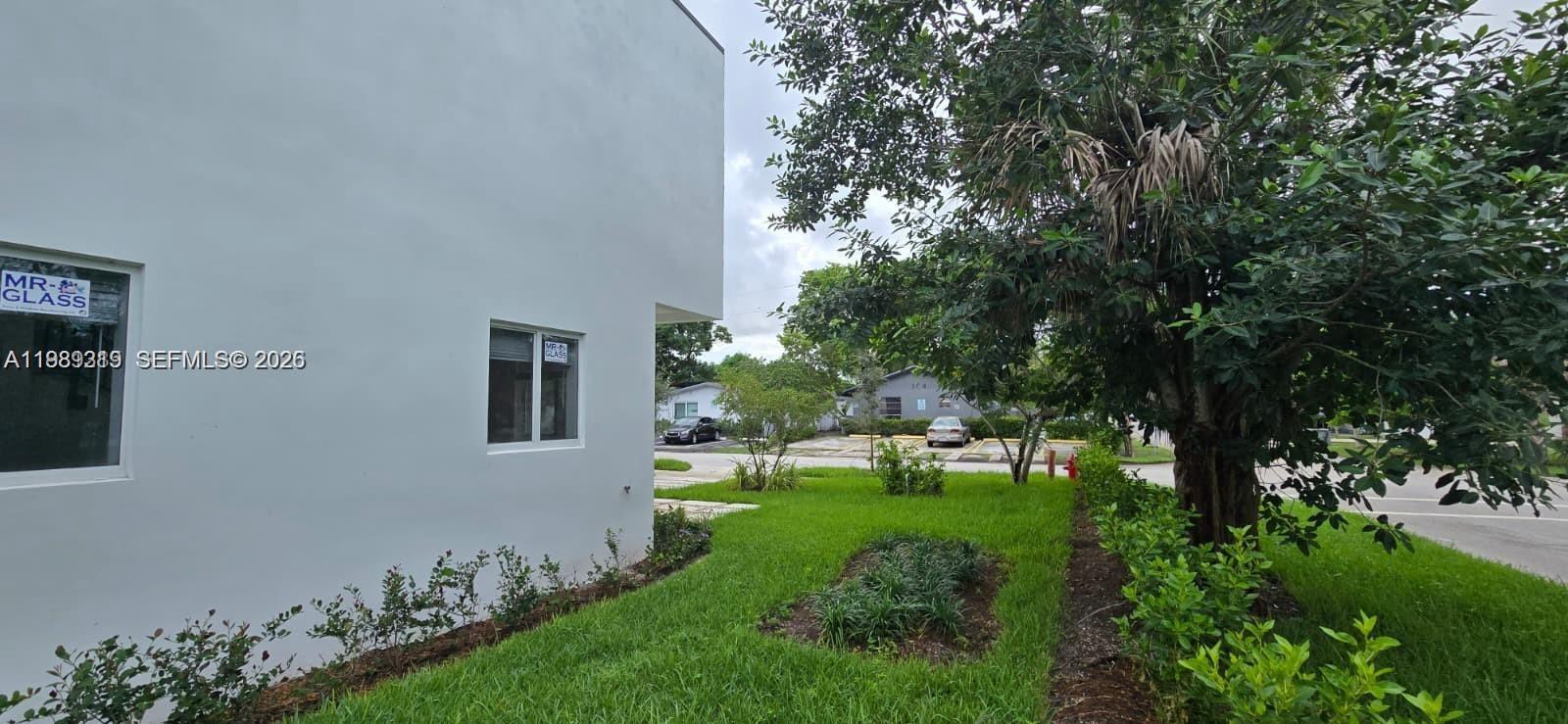A white exterior wall of a building features two windows with glass company stickers — 141 NW 11th St, Pompano Beach FL 33060, POMPANO BEACH, FL