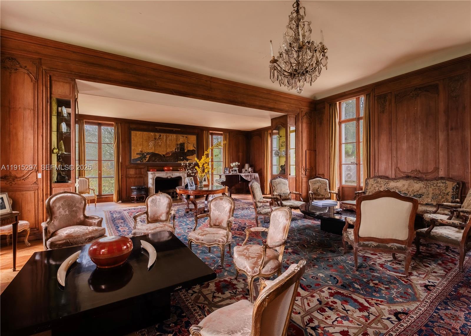 A spacious living room features wood-paneled walls, a crystal chandelier, and numerous antique-style chairs — 53 Route de Saint-Germain, TX 78860, TX