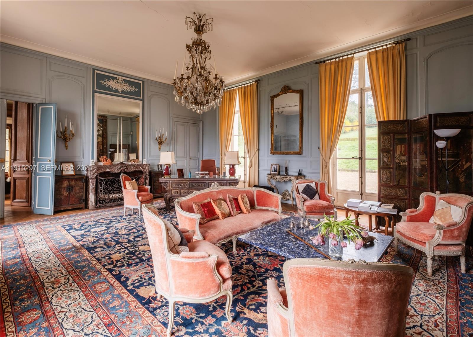 A formal living room features blue paneled walls, velvet furniture, a crystal chandelier, and rugs — 53 Route de Saint-Germain, TX 78860, TX