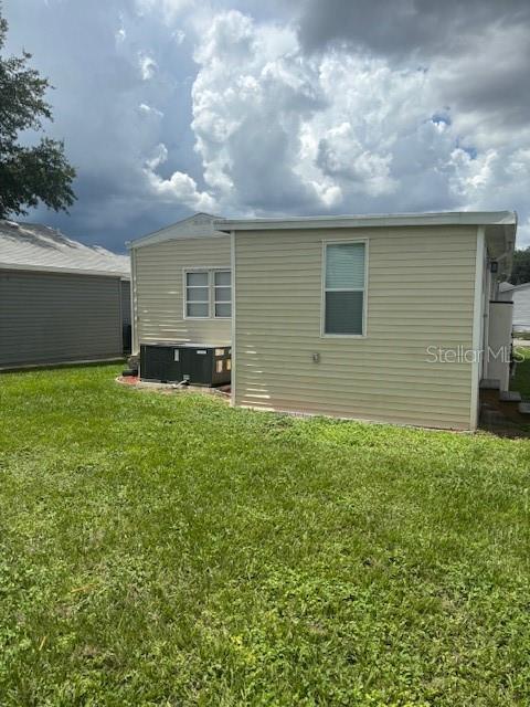The exterior of a light-colored mobile home features vinyl siding and an outdoor HVAC unit — 50989 HIGHWAY 27 UNIT 233, DAVENPORT, FL