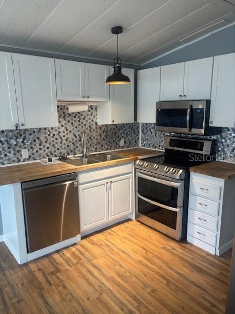 A kitchen features white cabinets, stainless steel appliances, a wood countertop, and a mosaic backsplash — 50989 HIGHWAY 27 UNIT 233, DAVENPORT, FL
